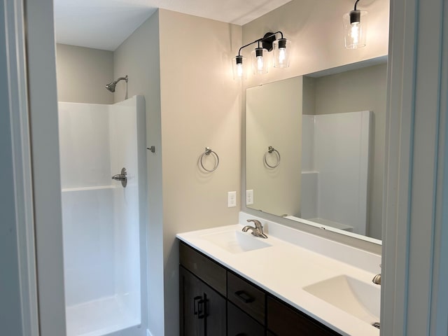 bathroom featuring a shower and double vanity