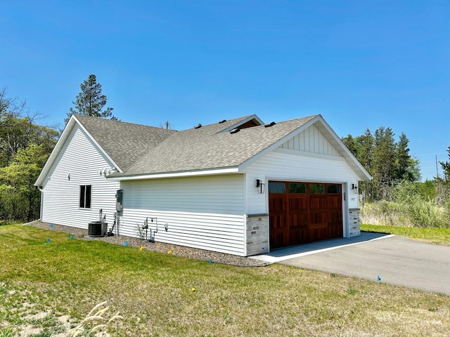 view of side of home featuring central AC, roof with shingles, and a lawn