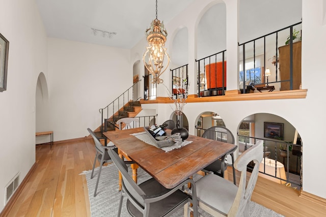 2622 159th Ave NE, Ham Lake, MN 55304 - dining space with arched walkways, a chandelier, wood finished floors, stairs, and a high ceiling