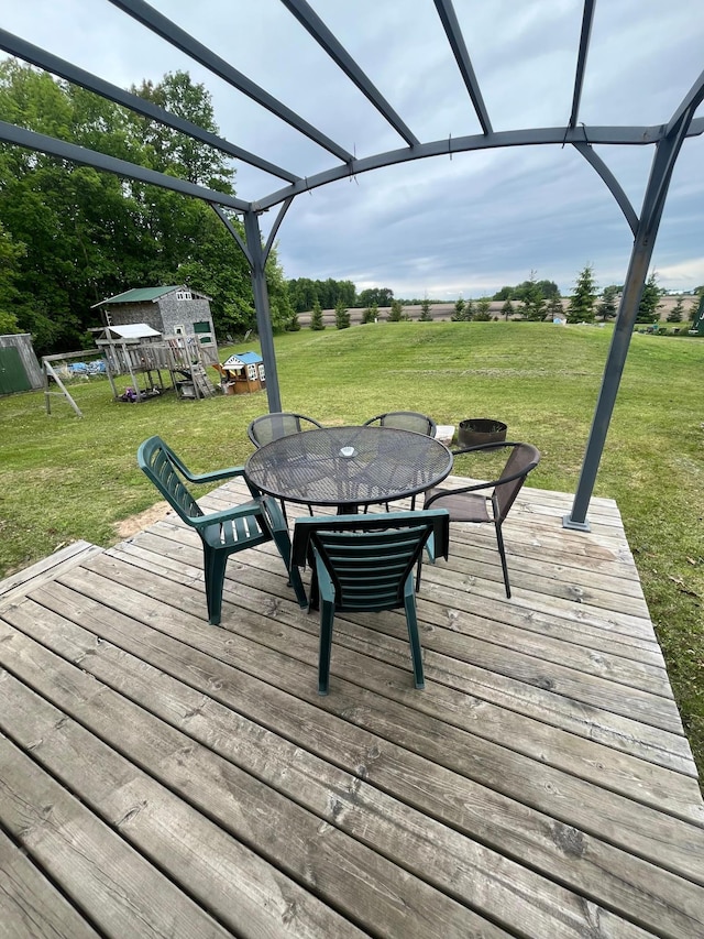 1141 Mahogany St, Mora, MN 55051 - wooden terrace featuring outdoor dining area, a yard, an outbuilding, and a pergola
