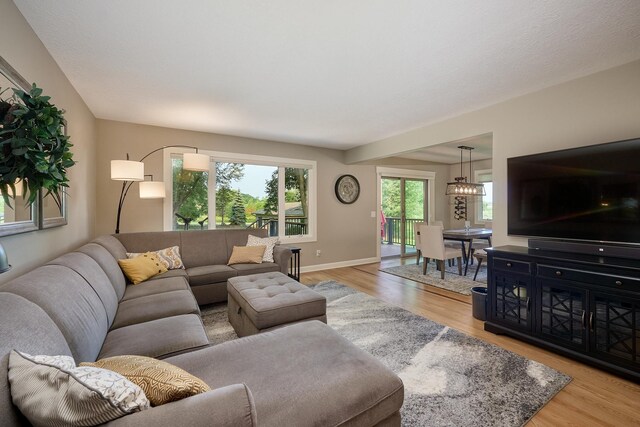 living room with light wood-style flooring, a chandelier, and baseboards
