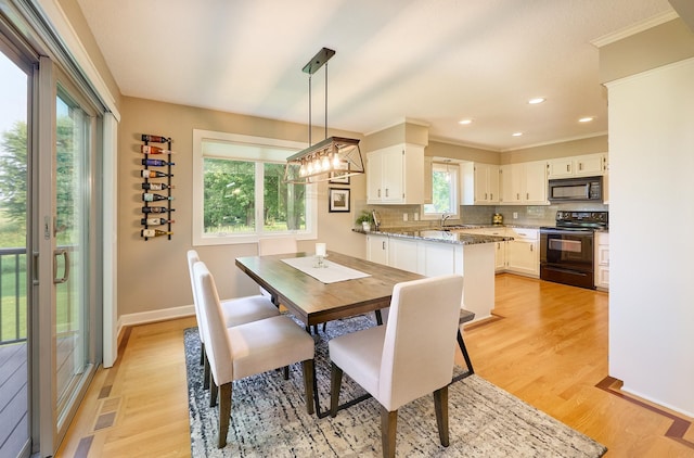 dining area featuring light wood-style floors, crown molding, baseboards, and recessed lighting