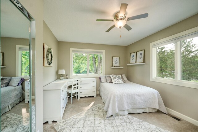 bedroom with light carpet, a desk, baseboards, and a ceiling fan