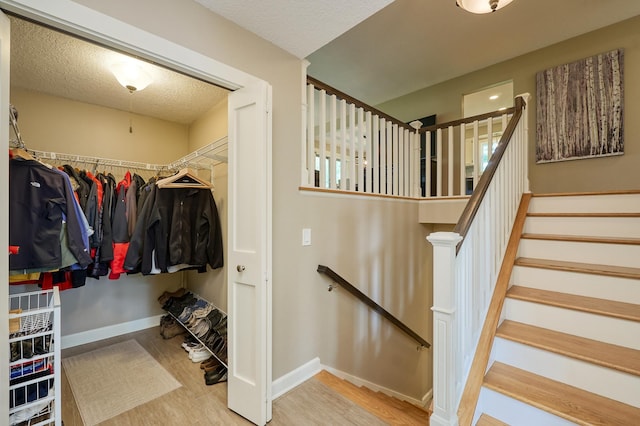staircase featuring wood finished floors, baseboards, and a textured ceiling