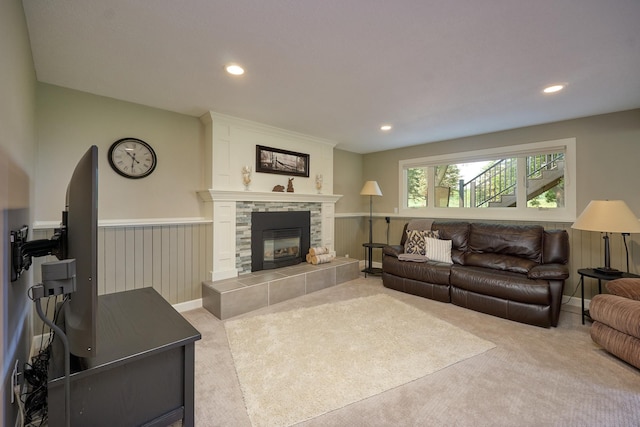 carpeted living room with a tiled fireplace, recessed lighting, and a wainscoted wall