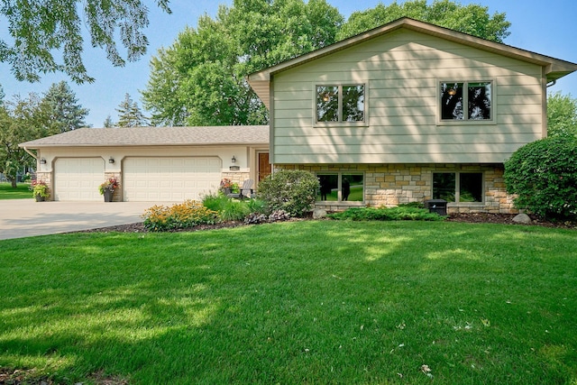 split level home with concrete driveway, a front lawn, and an attached garage