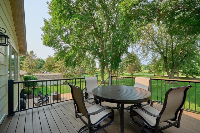 deck featuring outdoor dining area and a lawn