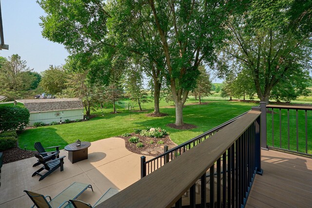 deck featuring an outdoor fire pit, a yard, and a patio