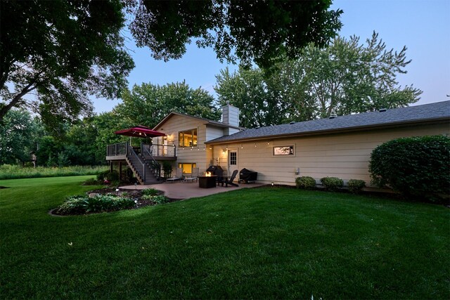 rear view of house with a wooden deck, a patio area, stairs, a yard, and a chimney