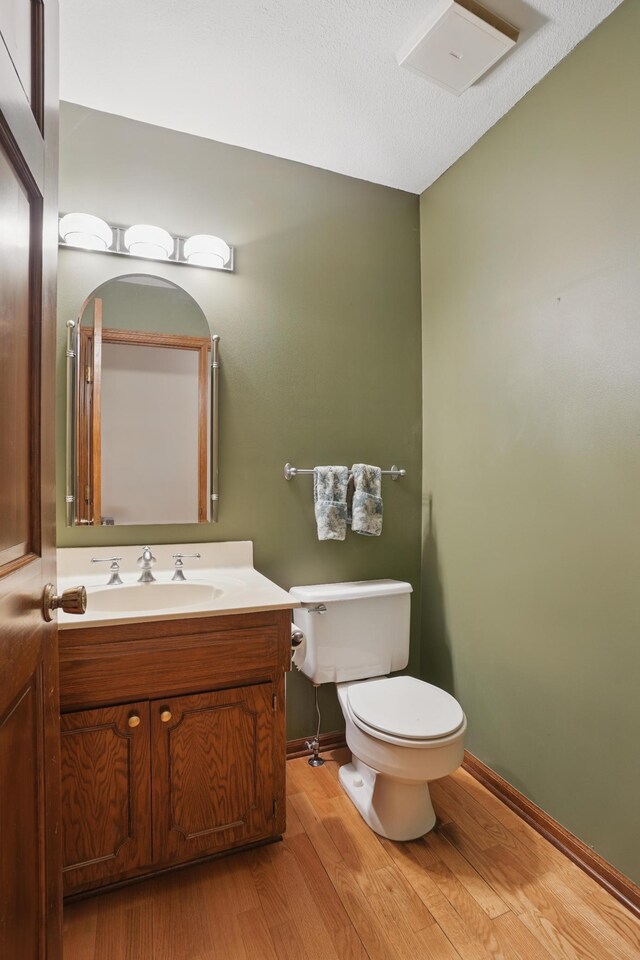 8681 144th Street Ct, Apple Valley, MN 55124 - half bathroom featuring wood finished floors, toilet, vanity, and baseboards