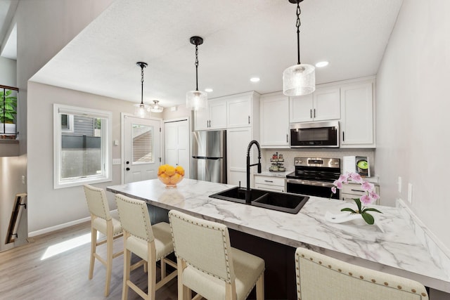 8754 Cottonwood Ln N, Maple Grove, MN 55369 - kitchen with stainless steel appliances, a sink, light wood-type flooring, light stone countertops, and baseboards