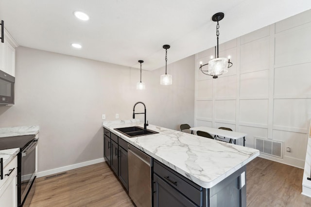 8754 Cottonwood Ln N, Maple Grove, MN 55369 - kitchen with black appliances, a peninsula, a sink, light wood finished floors, and baseboards