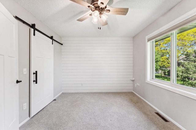 8754 Cottonwood Ln N, Maple Grove, MN 55369 - unfurnished bedroom featuring a barn door, light colored carpet, a textured ceiling, a ceiling fan, and baseboards