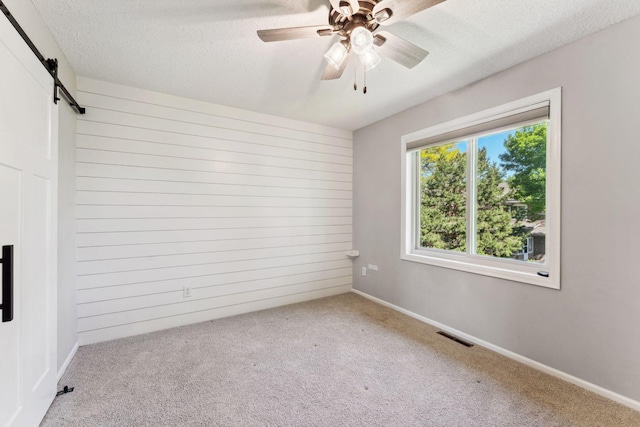 8754 Cottonwood Ln N, Maple Grove, MN 55369 - carpeted empty room with a barn door, ceiling fan, a textured ceiling, baseboards, and wooden walls