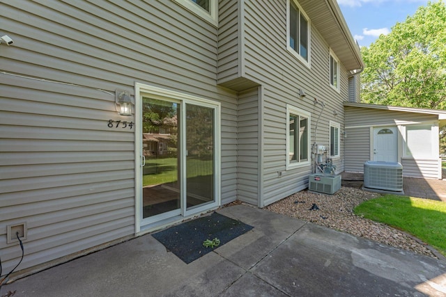 8754 Cottonwood Ln N, Maple Grove, MN 55369 - view of exterior entry with central AC and a patio