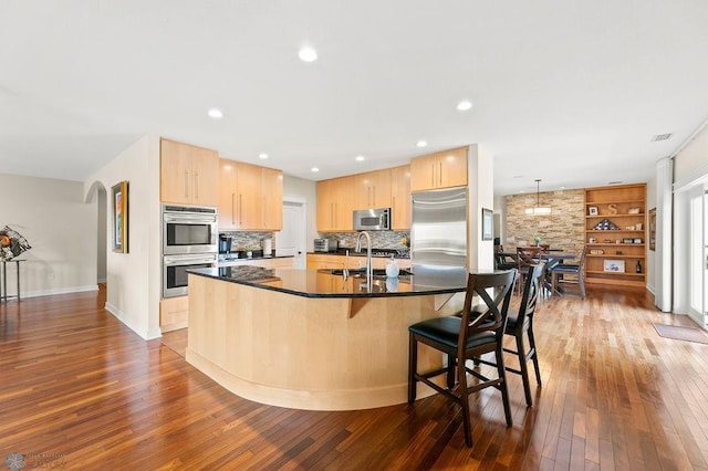 2501 30th Ave S Unit 201, Fargo, ND 58103 - kitchen featuring appliances with stainless steel finishes, light brown cabinetry, dark countertops, dark wood finished floors, and a spacious island