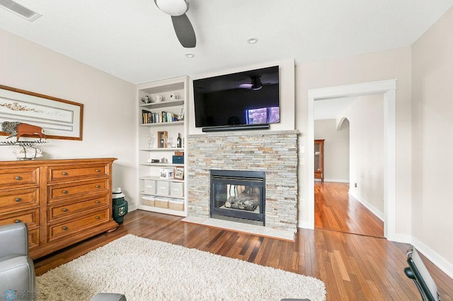 2501 30th Ave S Unit 201, Fargo, ND 58103 - living room featuring arched walkways, wood-type flooring, a ceiling fan, built in shelves, and a fireplace