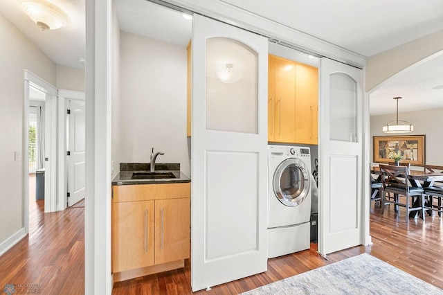 2501 30th Ave S Unit 201, Fargo, ND 58103 - clothes washing area with cabinet space, washer / dryer, wood finished floors, and arched walkways