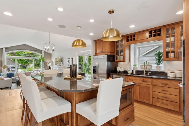 4084 Wild Goose Ln, White Bear Twp, MN 55110 - kitchen with a sink, stainless steel appliances, brown cabinetry, open floor plan, and a breakfast bar area