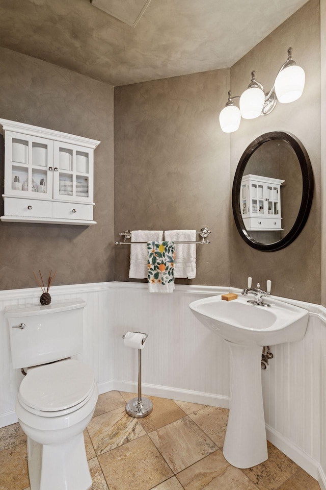 4084 Wild Goose Ln, White Bear Twp, MN 55110 - bathroom with toilet, wainscoting, stone finish flooring, baseboards, and a sink