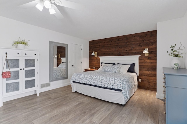4084 Wild Goose Ln, White Bear Twp, MN 55110 - bedroom featuring wooden walls, light wood-style flooring, a ceiling fan, and baseboards