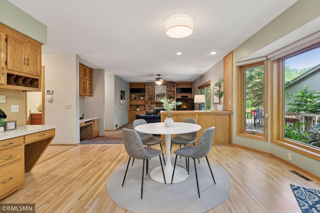 12762 Foliage Ave, Apple Valley, MN 55124 - dining room with a brick fireplace, built in shelves, light wood-style floors, baseboards, and ceiling fan