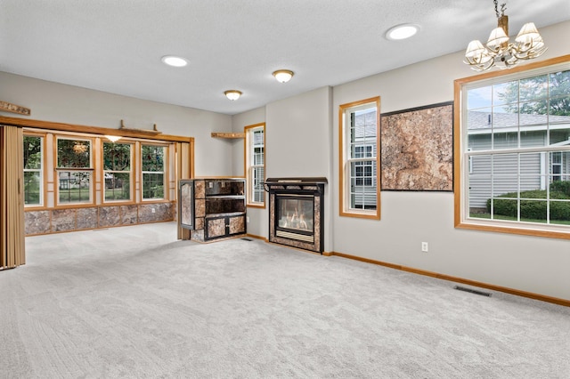351 100th Ct NE, Blaine, MN 55434 - unfurnished living room with carpet, a chandelier, a glass covered fireplace, and a textured ceiling