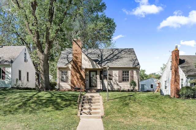 view of front facade with a front yard, a chimney, and a shingled roof