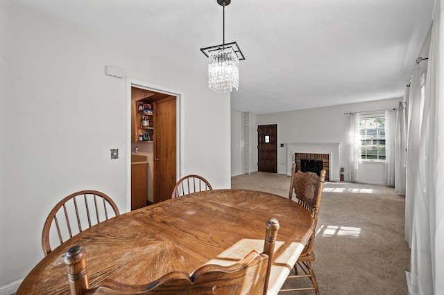 dining room featuring a chandelier, light carpet, and a fireplace