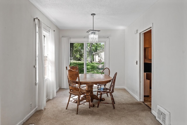 dining room with a textured ceiling, light carpet, baseboards, and a chandelier