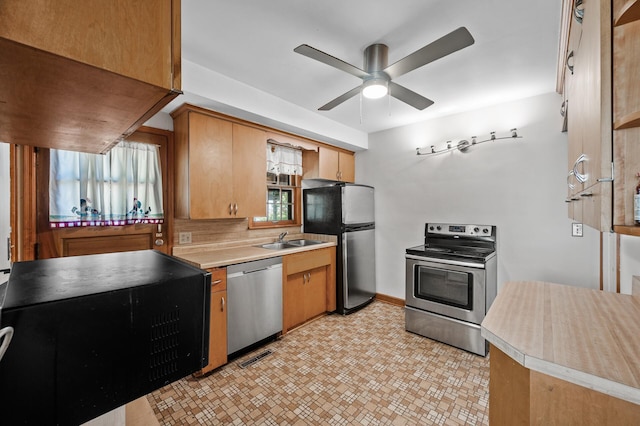 kitchen featuring stainless steel appliances, a sink, light countertops, and ceiling fan