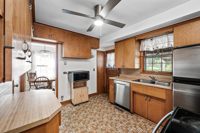 kitchen featuring appliances with stainless steel finishes, a sink, and brown cabinetry