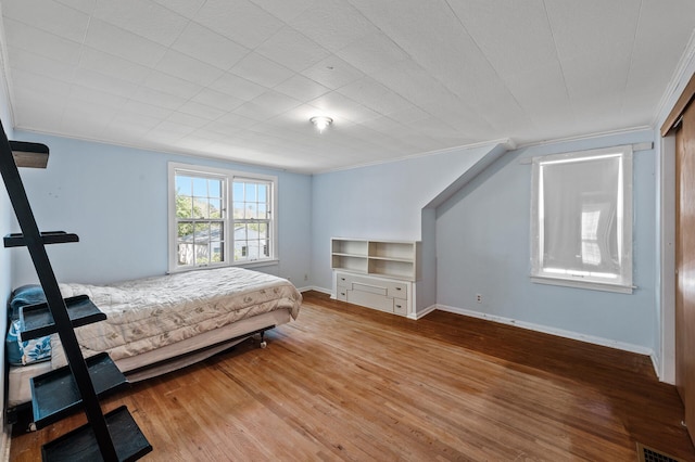bedroom featuring wood finished floors, baseboards, and crown molding