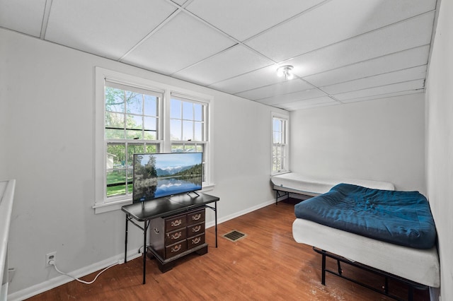 bedroom with wood finished floors, a paneled ceiling, and baseboards