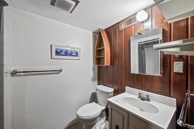 full bathroom featuring vanity, toilet, wooden walls, and a shower with shower curtain