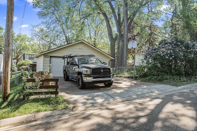 view of side of home featuring a detached garage and fence