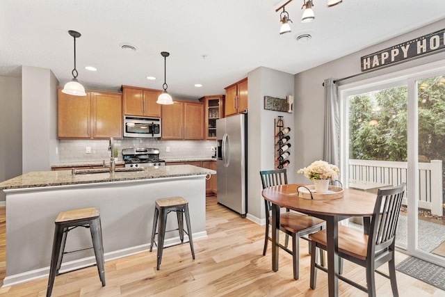 2119 Cedar Grove Trl, Eagan, MN 55122 - kitchen featuring appliances with stainless steel finishes, brown cabinetry, light wood-style flooring, a sink, and tasteful backsplash