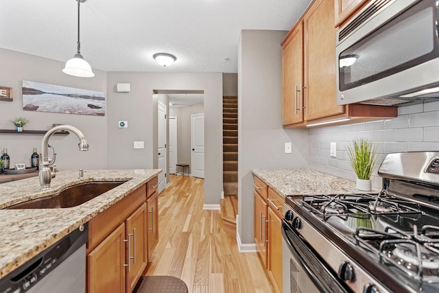 2119 Cedar Grove Trl, Eagan, MN 55122 - kitchen with appliances with stainless steel finishes, a sink, light wood-style flooring, tasteful backsplash, and decorative light fixtures