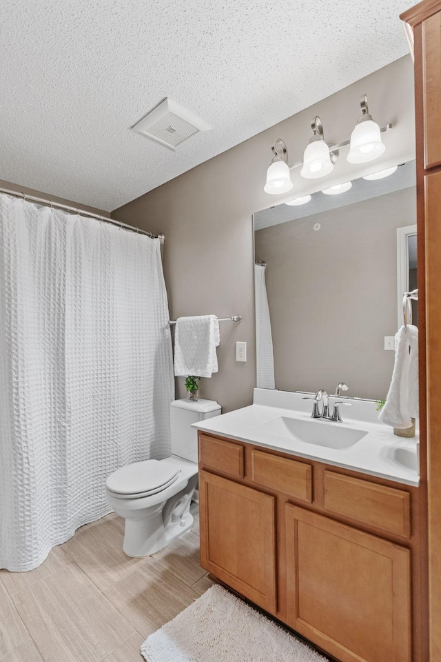 2119 Cedar Grove Trl, Eagan, MN 55122 - bathroom featuring vanity, toilet, a textured ceiling, wood finished floors, and a shower with shower curtain