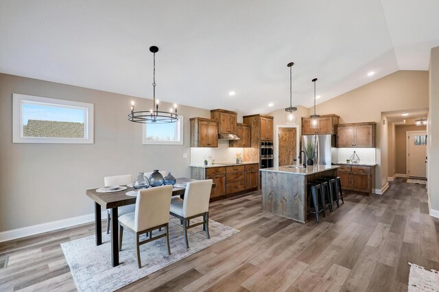 17795 Hoover St NW, Elk River, MN 55330 - dining space with vaulted ceiling, light wood-type flooring, a chandelier, and baseboards