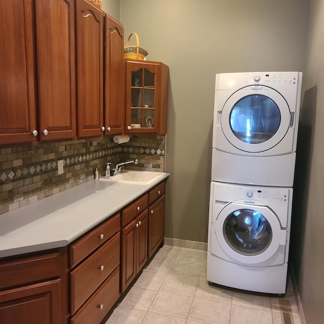 14473 Barnes Dr, Lake View Twp, MN 56501 - laundry room with stacked washer / drying machine, cabinet space, light tile patterned floors, and baseboards