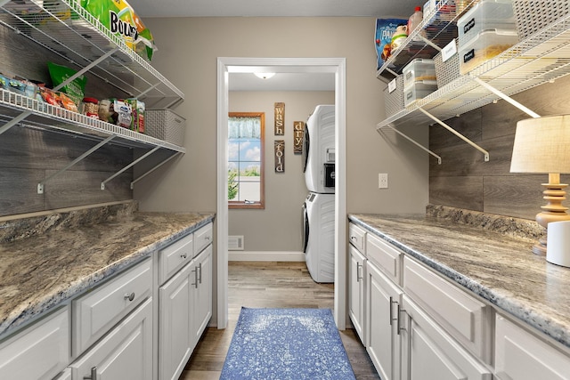 W10415 521st Ave, Prescott, WI 54021 - laundry room featuring stacked washer and clothes dryer, wood finished floors, and baseboards