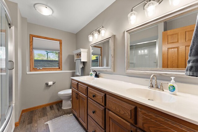 W10415 521st Ave, Prescott, WI 54021 - full bathroom featuring an enclosed shower, wood finished floors, toilet, baseboards, and double vanity