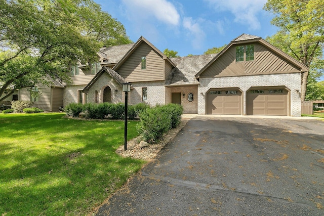 view of front of house featuring driveway, brick siding, an attached garage, and a front yard