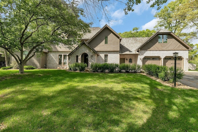 view of front of property with brick siding, a garage, a front lawn, and asphalt driveway