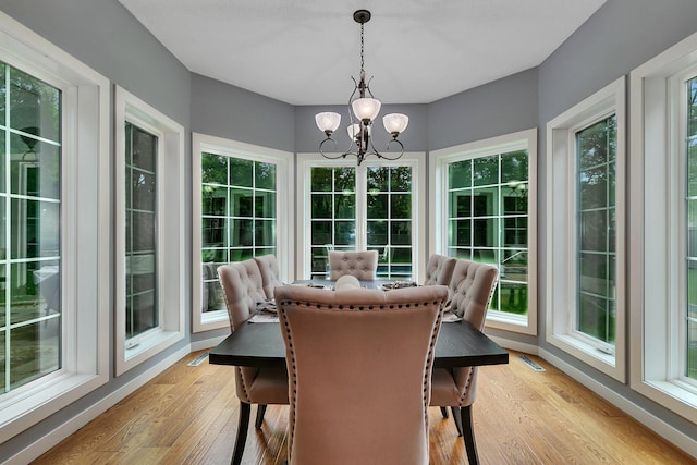 sunroom with a chandelier, wood finished floors, and healthy amount of natural light