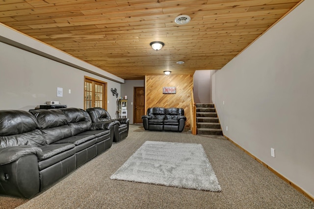 living room featuring wood ceiling, stairway, carpet, wooden walls, and baseboards