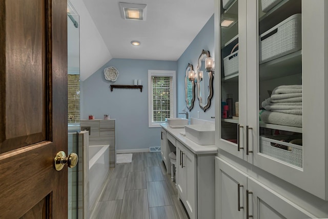 full bath featuring baseboards, a garden tub, double vanity, lofted ceiling, and a chandelier