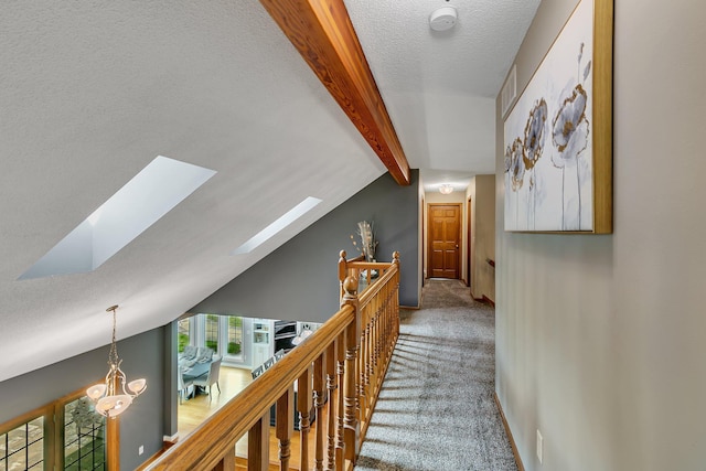 hall with carpet floors, a skylight, a textured ceiling, and baseboards