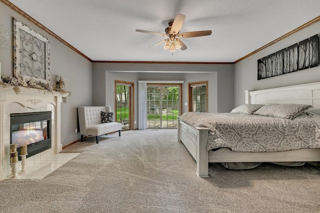 carpeted bedroom with ornamental molding, access to outside, a fireplace, a textured ceiling, and a ceiling fan